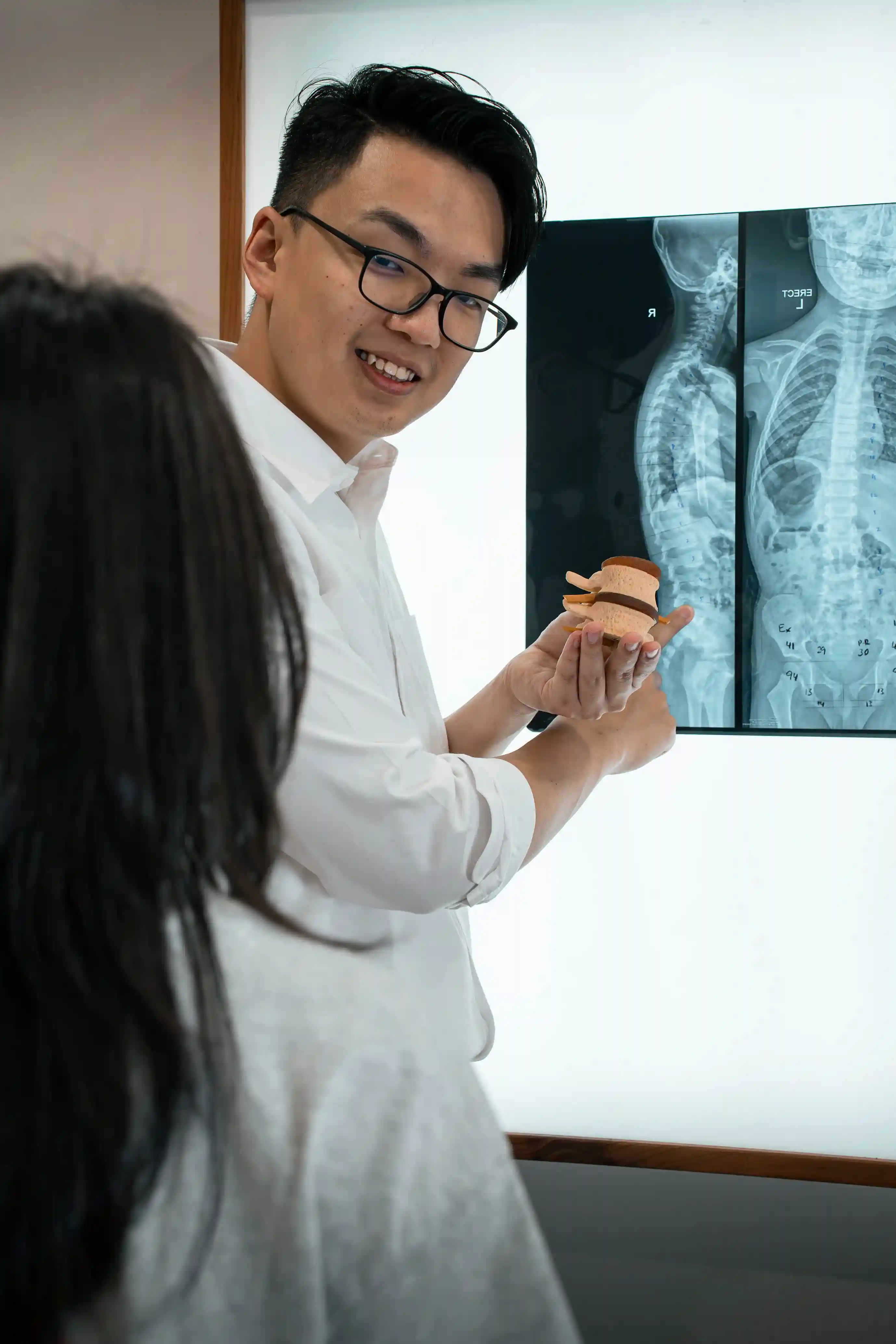 Dr. Derek explaining spinal alignment and slipped disc causes using a spine model and X-ray analysis at Value Gonstead Chiropractic Ampang.